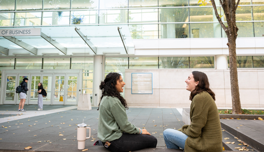 Two undergraduate students talk and laugh on a cement bench outside of Georgia Tech’s Scheller College of Business.