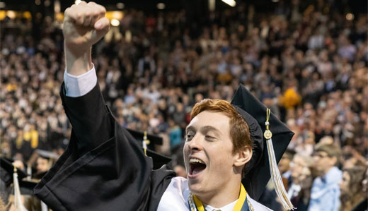 A student celebrates at Georgia Tech’s graduation ceremony while wearing his regalia.