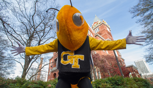 Buzz, Georgia Tech’s mascot, stands with his arms out in greeting in front of the iconic Tech Tower on campus in Atlanta, Georgia.