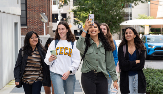 Undergraduate students on a sidewalk in Technology Square, where Georgia Tech’s campus meets Midtown Atlanta, pose for a selfie.