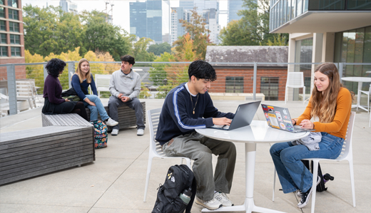 Georgia Tech students study outside, with the Atlanta skyline in the background.