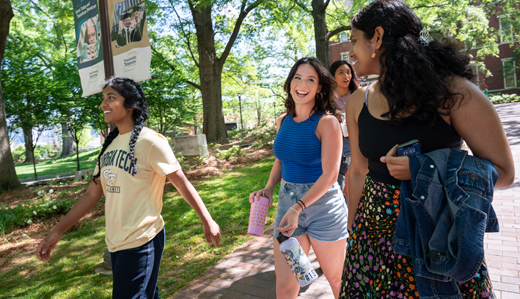 A group of undergraduate students at Georgia Tech walk on the sidewalk just beneath Tech Tower, heading to Harrison Square.